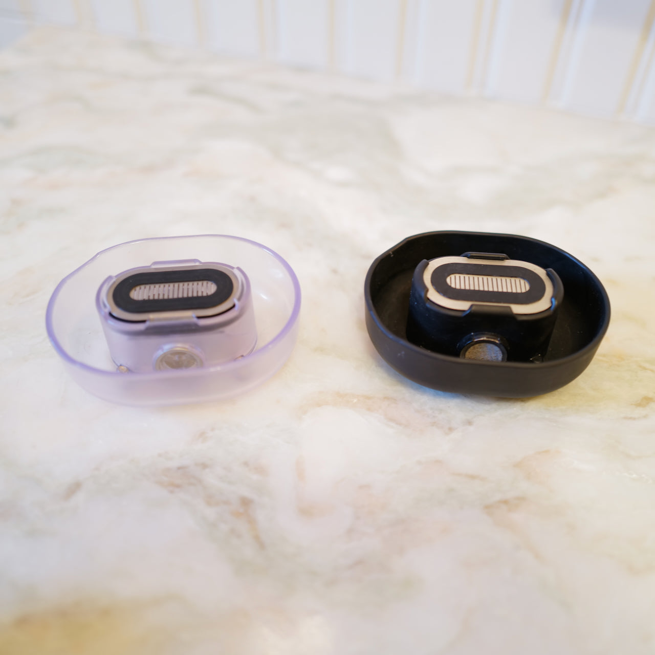 A pair of Razor Rinsers, in clear and black - made to effortlessly clean your razor, save water, and keep your sink clean while you shave.