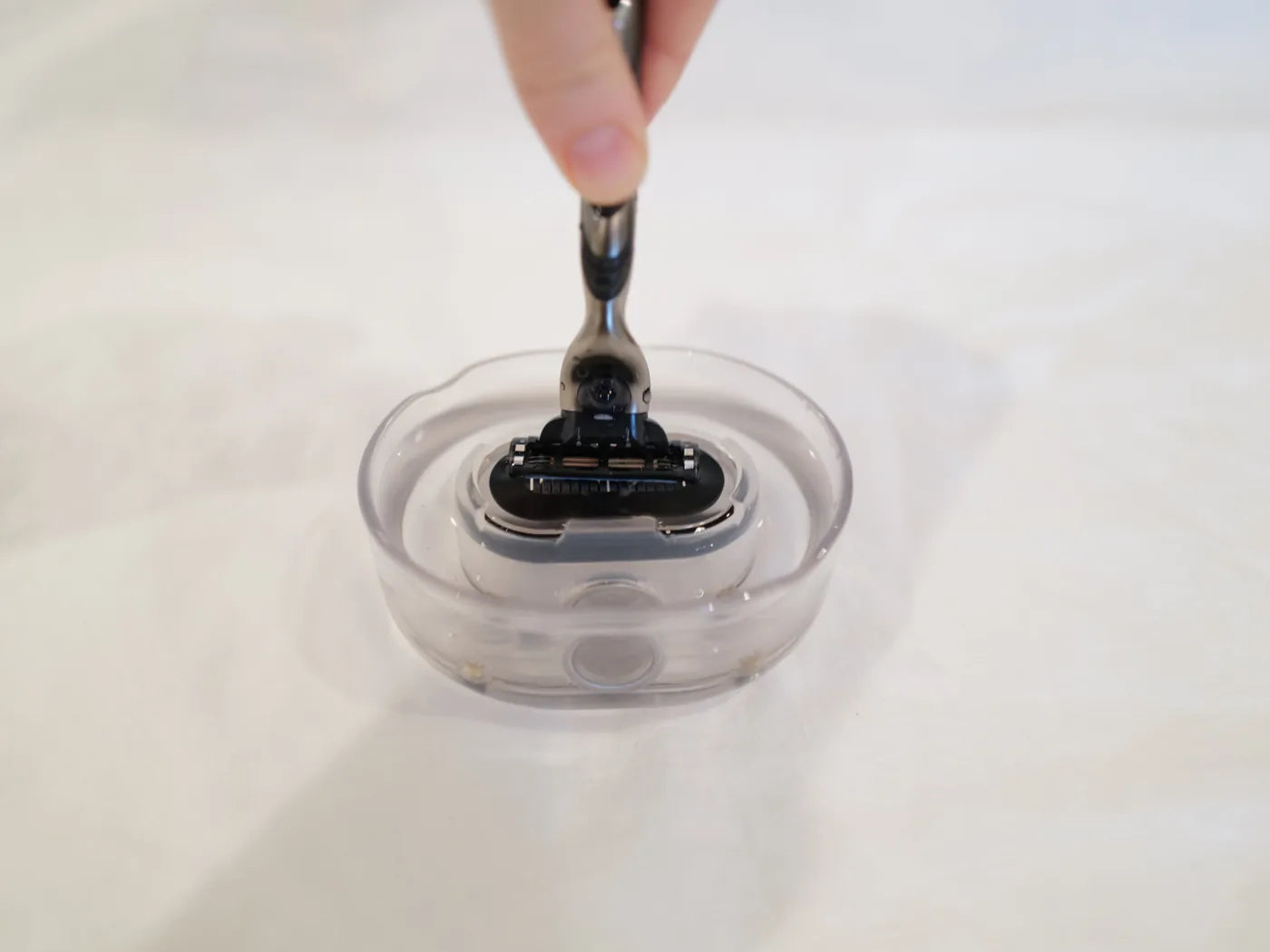 Pressing a cartridge razor onto the water jets of the Razor Rinser to clear the blades