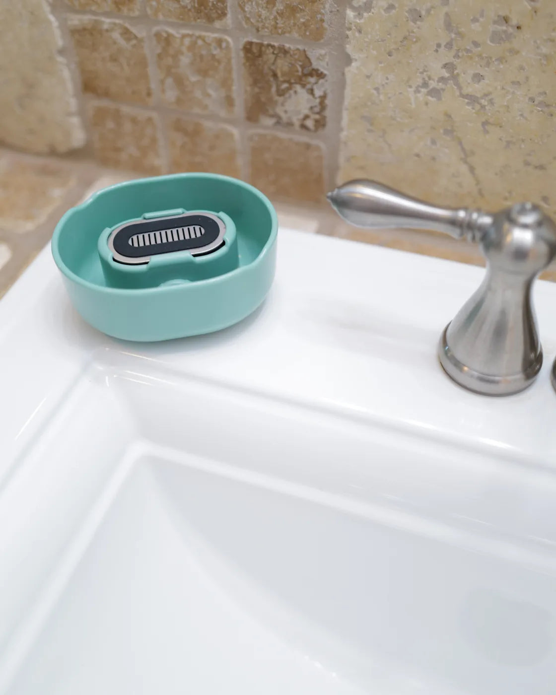 The Eucalyptus Razor Rinser® on a bright bathroom counter beside the sink.