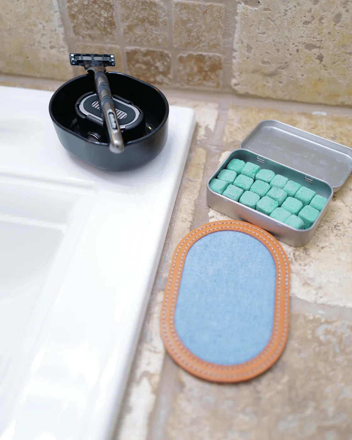 The full Clean Shave kit on a bathroom counter: Razor Rinser®, strop, and shave bombs.
